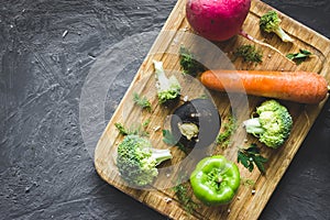 Pepper, carrot, radishes, broccoli and greens on wooden chopping board