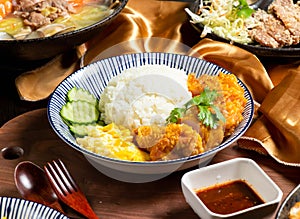 Pepper Chicken Rice with cucumber, sauce fork and spoon served in dish isolated on wooden board side view of asian food