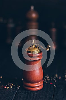 Pepper or coffee vintage wooden grinder on a dark black background