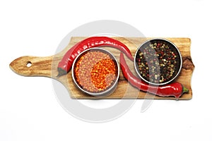 Pepper grains are red, black, white spices, float in a silver bowl. View from above. Isolated on white background.