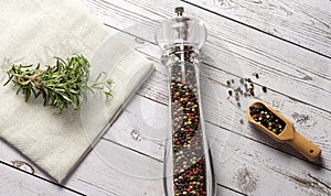 Pepper mill with fresh rosemary and kitchen towel on the wooden table. Food cooking background