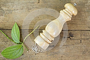 Pepper mill and leaves on wooden