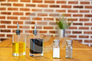 Pepper mill and salt shaker, with bottles of oil and vinegar, on a bamboo table