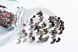 Pepper mix is sprinkled from a glass jar on white