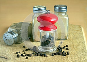 Pepper, pepper mill and spice jars on kitchen desk closeup