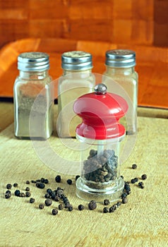 Pepper, pepper mill and spice jars on kitchen desk closeup