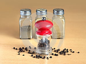 Pepper, pepper mill and spice jars on kitchen desk closeup