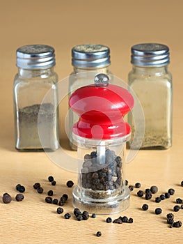 Pepper, pepper mill and spice jars on kitchen desk closeup