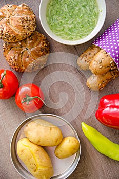 Pepper, potato, kaiser bun and baguette on wood table. Vegetarian bio food concept.