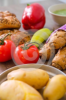 Pepper, potato, kaiser bun and baguette on wood table. Vegetarian bio food concept.