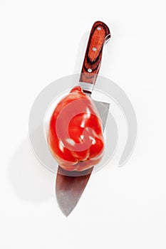 Pepper tomato cut with knife isolated on white