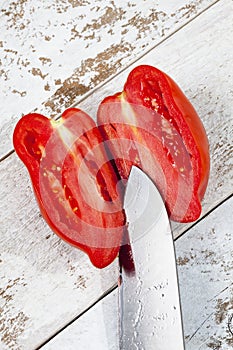 Pepper tomato cut with knife on white wood