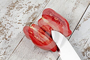 Pepper tomato cut with knife on white wood