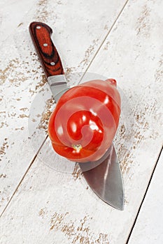 Pepper tomato cut with knife on white wood