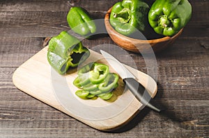 Pepper on a wooden cutting board on dark table/whole fresh paprika and cut on a board on a dark table, top view