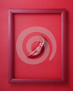 Pepper in wooden picture frame on red background