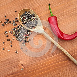 Pepper in a wooden spoon over rustic wooden background