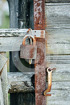 Peppered with dents padlock securing an old wooden door