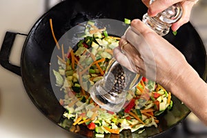 Peppering chinese food in wok