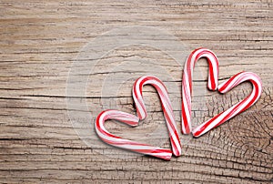 Peppermint Candy Canes in Heart Shapes on wooden background
