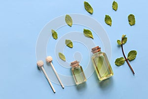 Peppermint essential oil in glass bottles on blue background