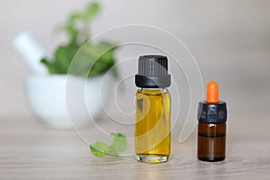 Peppermint essential oil in glass bottles on wooder background