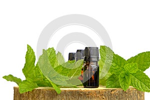 Peppermint essential oil isolated on white background. bottles and sprigs of mint on a wooden saw cut .Organic pure