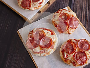 Pepperoni and Mozzarella Cheese Mini Pizzas served on Wooden Plates over White Food Paper