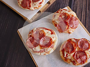 Pepperoni and Mozzarella Cheese Mini Pizzas served on Wooden Plates over White Food Paper photo