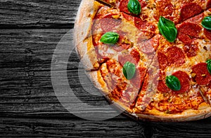 Pepperoni Pizza with Mozzarella cheese, salami, Tomato sauce, pepper, Spices and Fresh basil. Italian pizza on wooden table