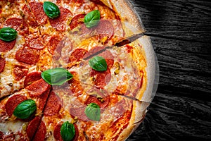 Pepperoni Pizza with Mozzarella cheese, salami, Tomato sauce, pepper, Spices and Fresh basil. Italian pizza on wooden table