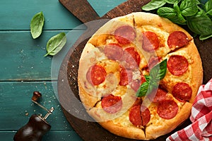 Pepperoni pizza. Traditional pepperoni pizza and cooking ingredients tomatoes basil on wooden table backgrounds. Italian
