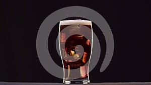 Pepsi foam in the glass forming cycle on a black background