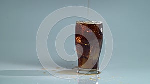 Pepsi is poured into a glass with ice. Blue background