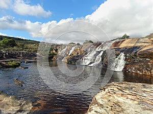 Beautiful view of waterfalls and lakes, amid rocks, tree trunks, vegetation and woods. photo