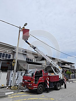 Outdoor scene of workers change streetlight bulb pole with the Rear-mount Ladder truck