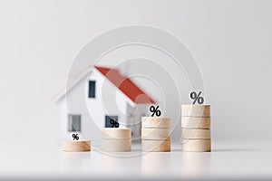 Percentage symbol for increasing interest rates on stacks of coins and model house. Interest rates increase, home loan, mortgage,