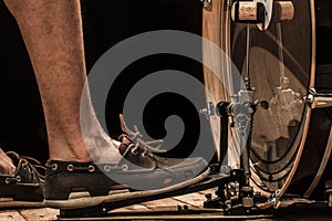 percussion instrument, bass drum with pedal on wooden Board with black background, men's foot