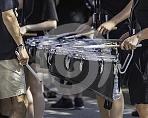 several percussionists of a marching band drum line warming up for a parade
