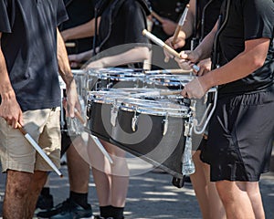 several percussionists of a marching band drum line warming up for a parade