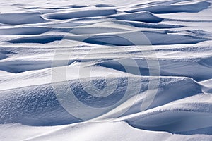 Perfect abstract texture of winter snow, mounds of frozen blue snow. Wavy surface of firn field