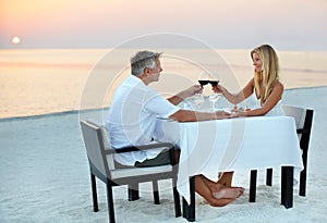 The perfect anniversary. a mature couple enjoying a romantic dinner on the beach.