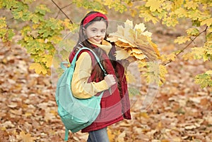 perfect autumn day of cheerful girl with school bag and maple leaves arrangement walking in fall season park in good