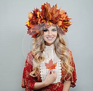Perfect autumn woman in bright fall leaves crown holding red maple leaf