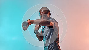 Perfect biceps. Muscular young african man exercising with dumbbells while standing against colorful background