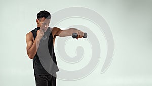 Perfect biceps. Muscular young african man exercising with dumbbells while standing against grey background