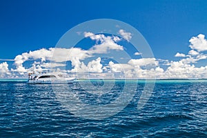 Perfect blue sea view with white boat on tropical sea, clouds and blue sky. Idyllic seascape