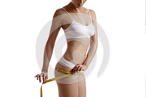 Perfect body of girl in white underwear measuring herself, posing isolated on white. Plastic surgery and aesthetic