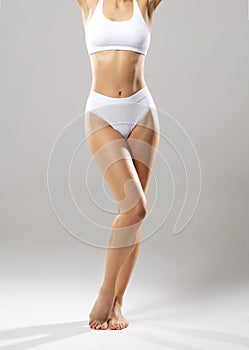 Perfect body of young and beautiful woman in swimsuit  on white. Weight loss, diet, sport and fitness concepts.