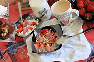 Perfect breakfast: crunchy granola with yoghurt and strawberries with a cup of milk coffee on marble table. Good morning. blurred